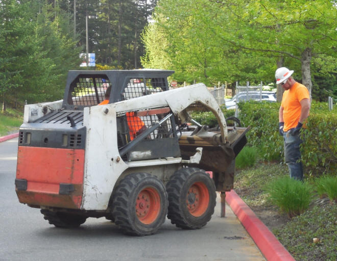 Bobcat drilling holes for a driven post rental fence.