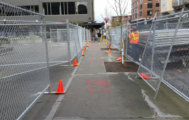 Setting up rental fencing for an urban construction site.